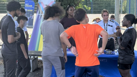 Police officers engage with young people around a trestle table.
